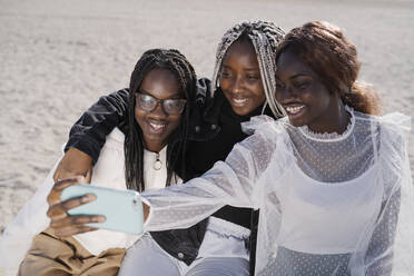 Porträt von glücklichen Teenager-Freundinnen, die ein Selfie am Strand machen - MPPF00584