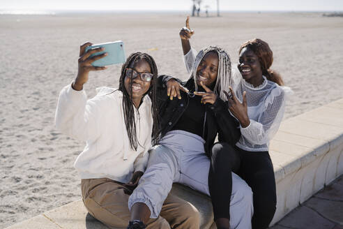 Portrait of happy teenage girlfriends taking a selfie at the beach - MPPF00586