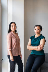 Portrait of confident female colleagues against wall at office - CAVF76468