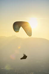 Paraglider silhouette flying at sunset - CAVF76527