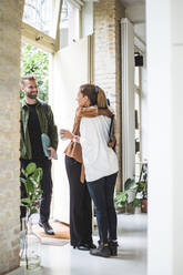 Eine Architektin begrüßt einen Mitarbeiter, während ein männlicher Unternehmer am Eingang steht - MASF16858