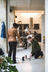 Male and female architects working while freelancer sitting in background at home - MASF16868