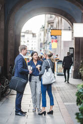 Mature businesswoman standing with coworkers in city - MASF16933