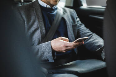 Midsection of mature businessman using phone while sitting in car - MASF16947