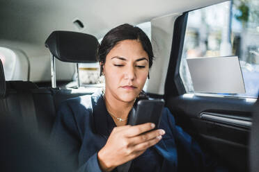 Geschäftsfrau benutzt Smartphone während der Fahrt im Auto - MASF16949