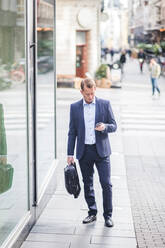 Älterer Geschäftsmann, der sein Smartphone benutzt, während er in der Stadt steht - MASF16957