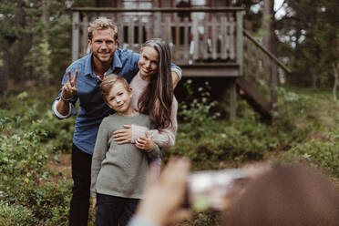 Portrait of smiling family taking pictures while standing in backyard - MASF17001