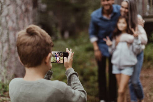 Junge fotografiert seine Familie mit dem Handy, während er im Hinterhof steht - MASF17002