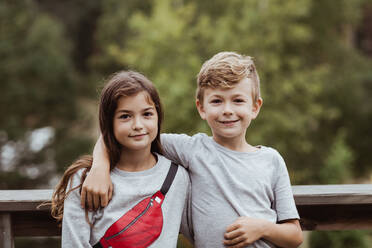 Portrait of smiling brother arm around standing with sister against railing - MASF17018