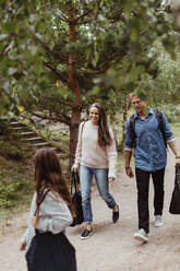 Eltern, die ihre Tochter beim Spaziergang auf einem Waldweg in voller Länge betrachten - MASF17020