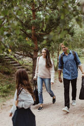 Full length of parents looking at daughter while walking on footpath in forest - MASF17020