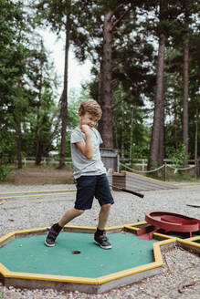 Volle Länge des fröhlichen Jungen spielen Minigolf im Hinterhof während der Ferien - MASF17040