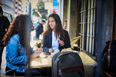 Lesbisches Paar im Gespräch in einem Straßencafé in der Stadt während des Urlaubs - MASF17170