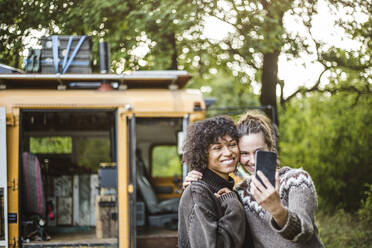 Frau macht Selfie mit Freund vor Wohnwagen beim Camping im Wald - MASF17264