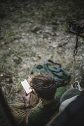 Hohe Winkel Ansicht des Mannes mit Smartphone gegen Wohnmobil während Camping - MASF17275