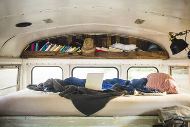 Laptop and crumpled blanket on bed in camper vehicle - MASF17313