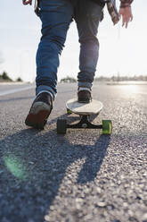 Anonymer Mann auf Longboard während der goldenen Stunde - CAVF76689