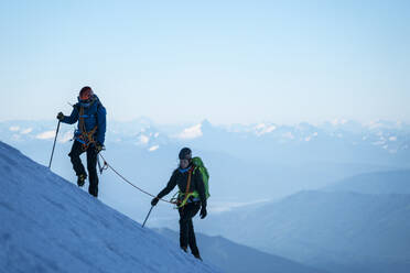 Two female mountaineers hike up a glacier on Mt. Baker, WA. - CAVF76736