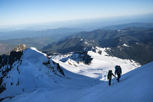 Zwei Sportler wandern auf einem Gletscher des Mt. Baker im Schatten des Gipfels. - CAVF76737