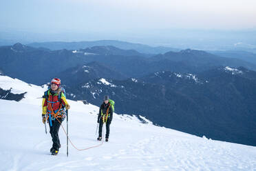 A female mountaineer looks up determinedly at the summit of Mt. Baker - CAVF76738