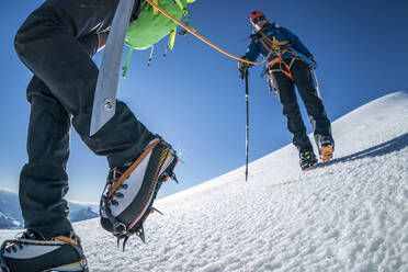 Eine Bergsteigerin in Steigeisen geht den Weg über einen Gletscher. - CAVF76747