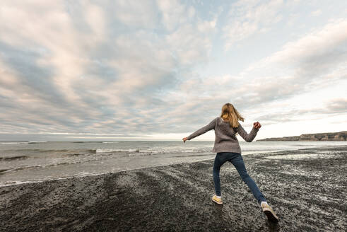 Tween girl throwing rocks on New Zealand coast - CAVF76753