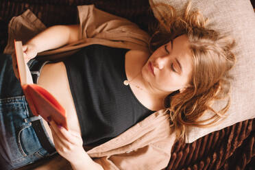 Hohe Winkel Ansicht der Teenager-Mädchen lesen Buch auf dem Bett liegend zu Hause - CAVF76809