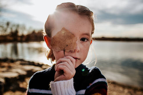Porträt eines Mädchens, dessen Gesicht zur Hälfte von einem Blatt bedeckt ist - CAVF76829