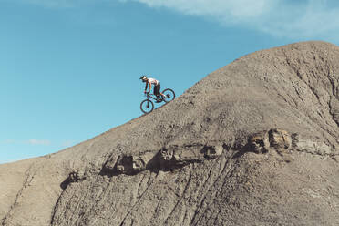 Seitenansicht eines Mountainbikers in steilem Wüstengelände - CAVF76962