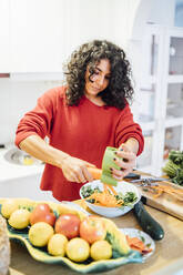 Brunette woman making a healthy green salad. - CAVF76975