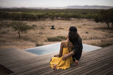 Rear view of couple sitting on deck of a lodge, Cape Town, South Africa - MJRF00258