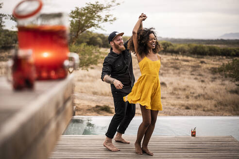 Glückliches Paar tanzt auf dem Deck einer Lodge, Kapstadt, Südafrika - MJRF00267