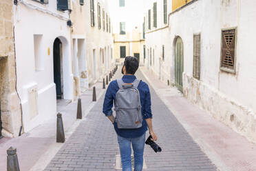 Rückansicht eines Mannes mit Kamera bei der Erkundung der Stadt, Mao, Menorca, Spanien - JPTF00476