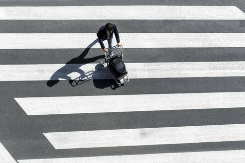 Man on zebra crossing pushing baggage cart, top view - JPTF00478