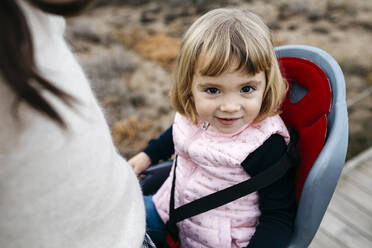 Portrait of toddler girl in child's seat of a bicycle - JRFF04131