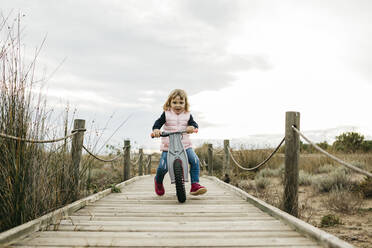 Kleinkind mit Gleichgewichtsfahrrad auf einer Promenade auf dem Lande - JRFF04144