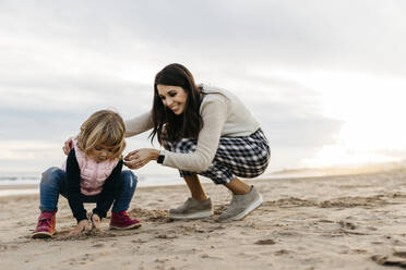 Glückliche Mutter und Tochter spielen bei Sonnenuntergang am Strand - JRFF04167