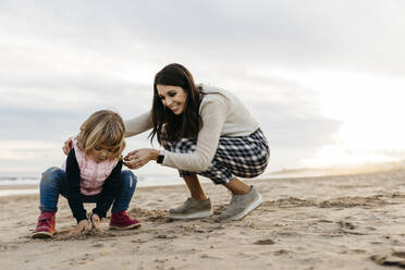 Happy mother and daughter playing on the beach at sunset - JRFF04167