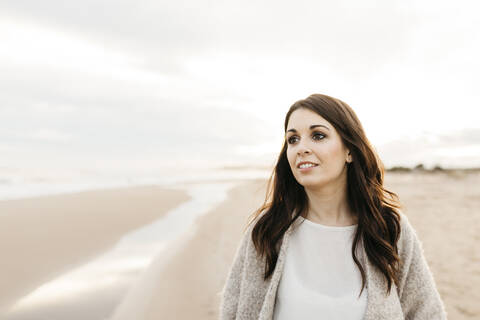 Porträt einer jungen Frau an einem abgelegenen Strand bei Sonnenuntergang, lizenzfreies Stockfoto
