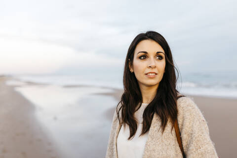 Porträt einer jungen Frau an einem abgelegenen Strand bei Sonnenuntergang, lizenzfreies Stockfoto