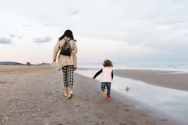 Rückansicht von Mutter und Tochter, die bei Sonnenuntergang am Strand laufen - JRFF04181