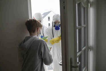 Scientists wearing protective clothing informing people at the door - KMKF01236