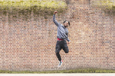 Junger Mann springt vor eine Ziegelmauer - WPEF02709