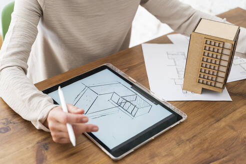 Frau arbeitet an einem Architekturmodell und einem digitalen Plan auf einem Schreibtisch im Büro - AFVF05602