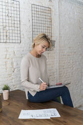 Reife Frau bei der Arbeit sitzt auf dem Schreibtisch im Architekturbüro - AFVF05632