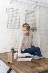 Reife Frau bei der Arbeit sitzt auf dem Schreibtisch im Architekturbüro - AFVF05635