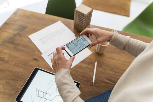 Close-up of woman in architectural office taking cell phone picture of construction plan - AFVF05638