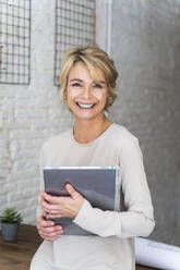 Porträt einer lächelnden reifen Frau im Büro, die ein Grafiktablett hält - AFVF05646