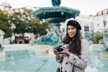 Junge Reisende mit Kamera am Springbrunnen des Rossio-Platzes, Lissabon, Portugal - DCRF00122