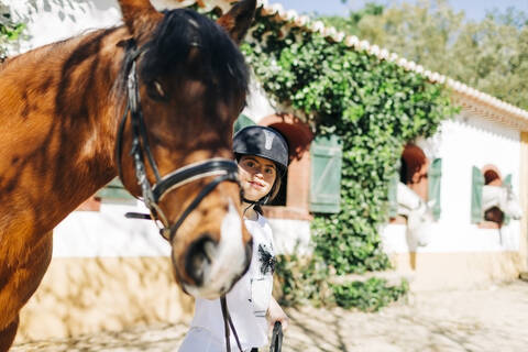 Teenager with down syndrome taking care of horse and preparing horse to ride stock photo